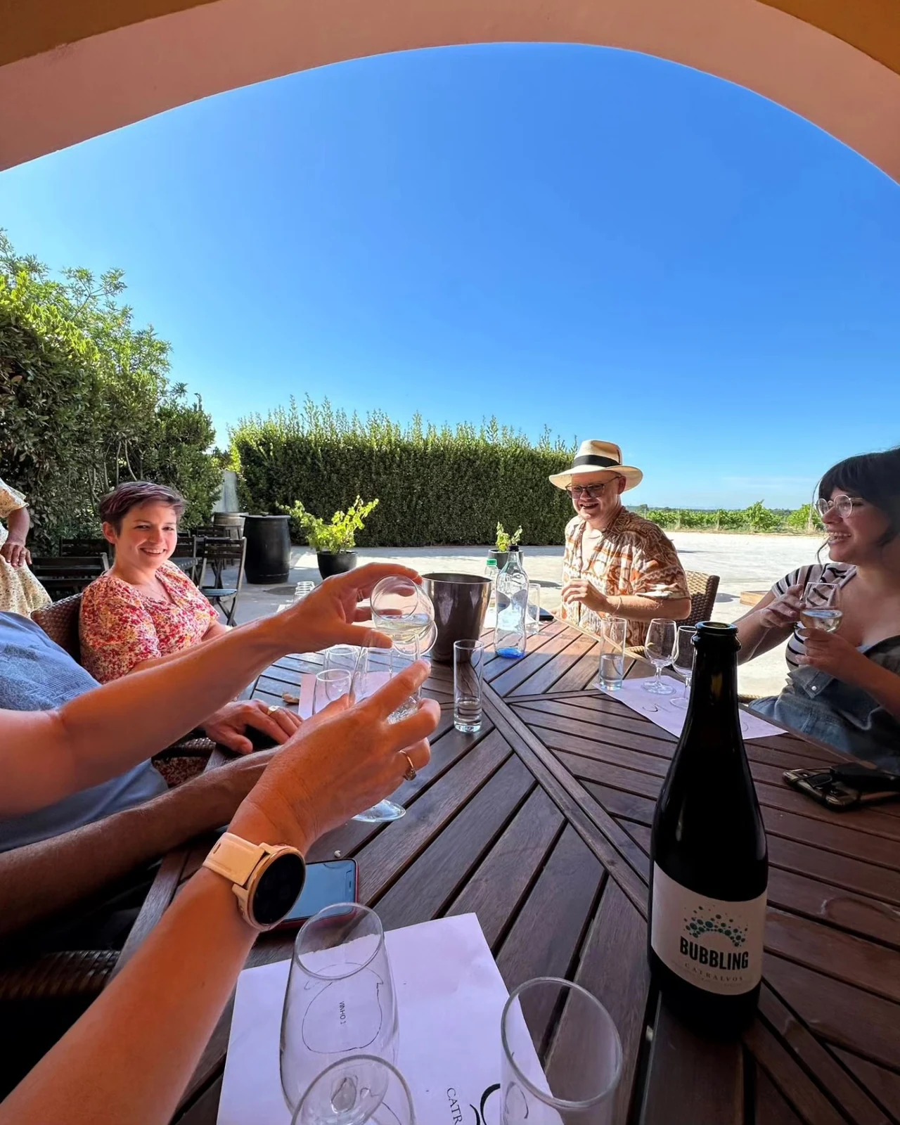 Guests raising Portuguese wine glasses together beneath a stone arch.