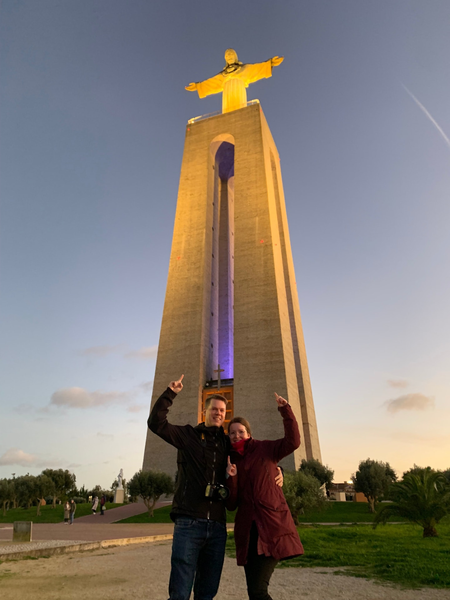A couple sharing a private evening beneath the illuminated Cristo Rei monument.