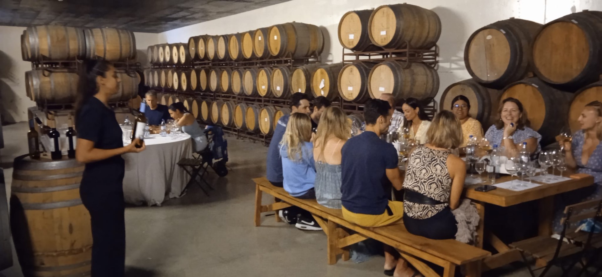 Colleagues gathered around a guided tasting inside a Portuguese barrel cellar.